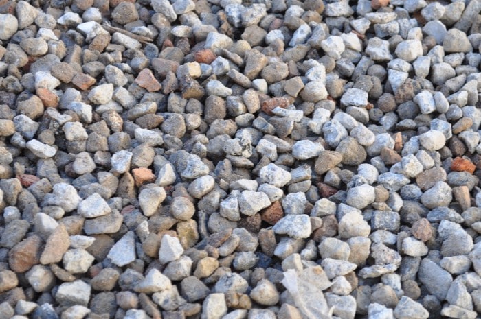 n image showing a pile of 20mm recycled aggregate. The aggregate consists of crushed concrete and other construction waste materials that have been carefully processed and graded to create a durable and eco-friendly product. The grayish tone of the aggregate indicates its recycled nature. This versatile material can be used for various construction and landscaping applications, such as driveways, pathways, and as a base for paving projects. Its sustainable composition makes it an excellent choice for environmentally conscious projects.