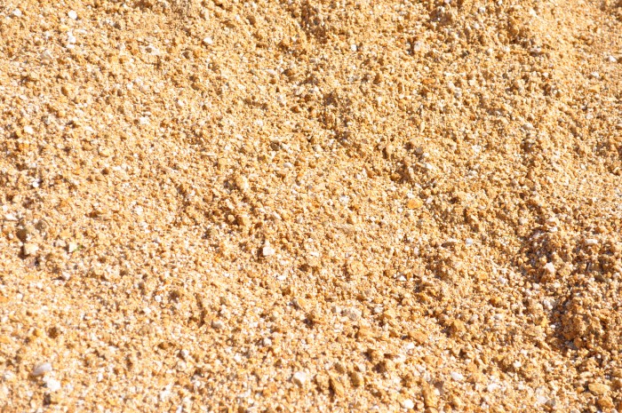 A close-up image of decomposed granite in a golden hue. The granules are finely textured and range in size from small pebbles to sand-like particles. The rich golden color adds warmth and elegance to outdoor spaces. This versatile landscaping material is perfect for pathways, driveways, and garden beds, providing a natural and aesthetically pleasing surface. Available at Parklea Sand & Soil Australia.