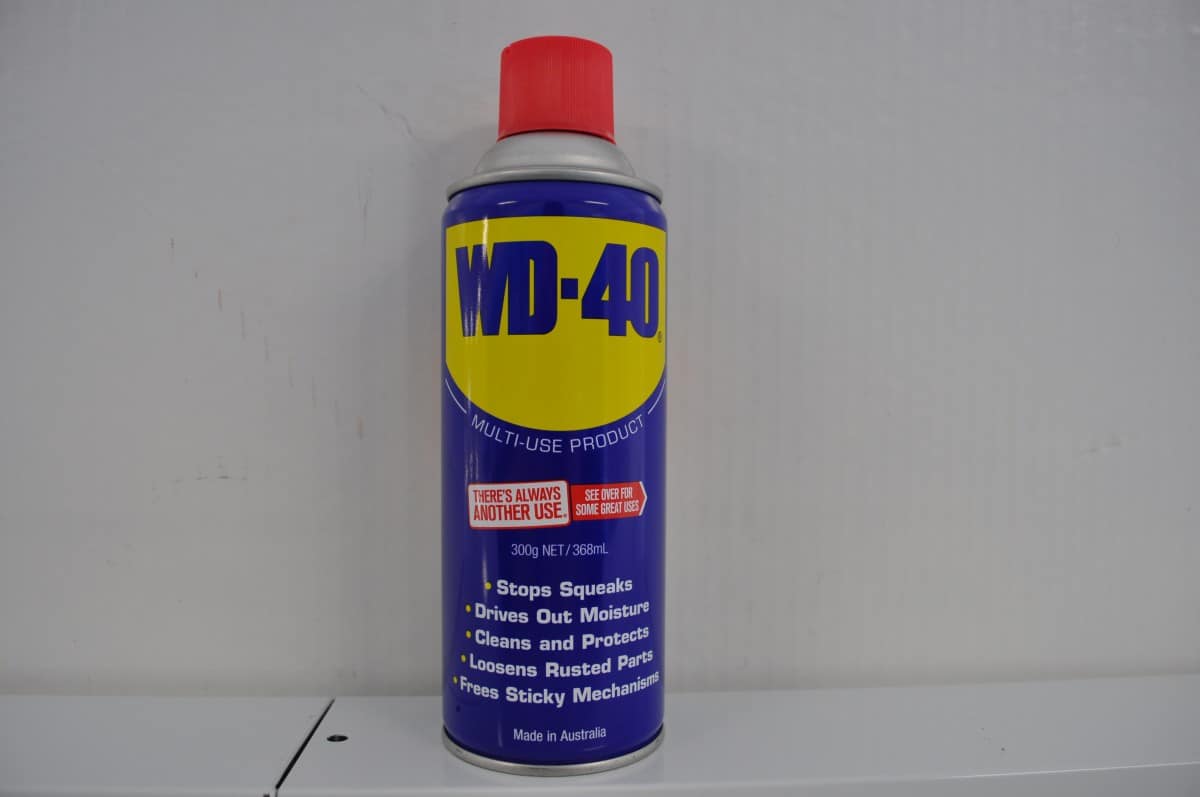 A close-up view of a blue and yellow can of WD-40, a multi-purpose lubricant and penetrating oil. The can is positioned against a clean white background, with the brand logo prominently displayed. The product is widely recognized for its versatility and ability to lubricate, protect, and loosen rusted parts. The can's label contains important product information and instructions for use, making it a trusted choice for various maintenance and DIY projects.