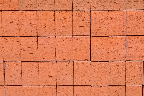 A stack of common bricks displayed on the Parklea Sand and Soil website's portfolio page. The bricks are uniform in shape and size, with a reddish-brown color and a textured surface. They are neatly stacked, showcasing their durability and versatility for various construction and landscaping projects.