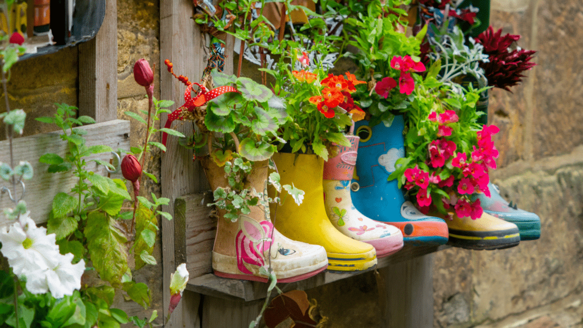 Colourful rain boots repurposed as flower pots, hung vertically. Creative recycle landscaping ideas by Parklea Sand & Soil Australia.